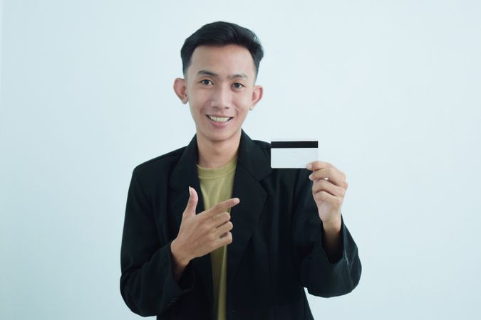 Asian businessman in suit and tshirt holding white credit card