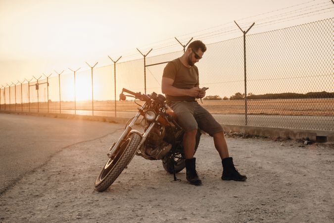 Man sitting on motorcycle and surfing mobile