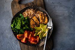 Healthy fresh meal with avocado, grains, tomatoes & spinach on kitchen counter with copy space