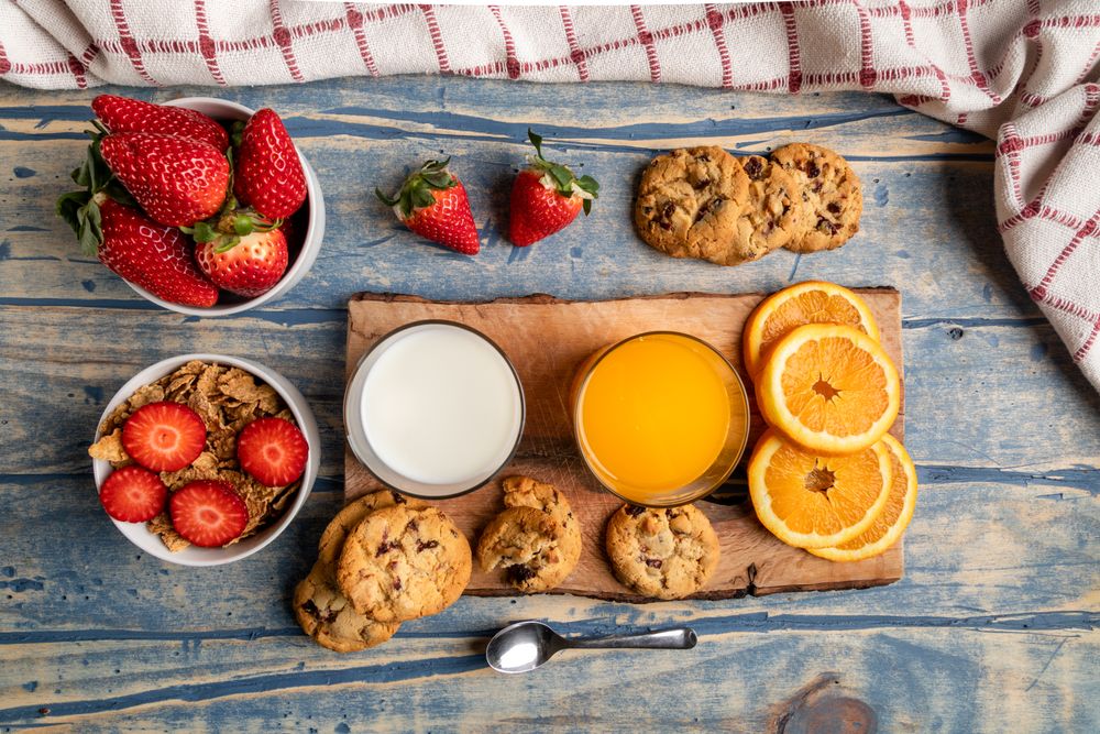 Glasses near fruits and cookies on table near napkin