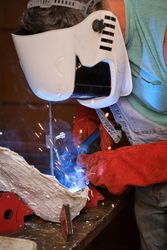 Welder in protective mask working in workshop