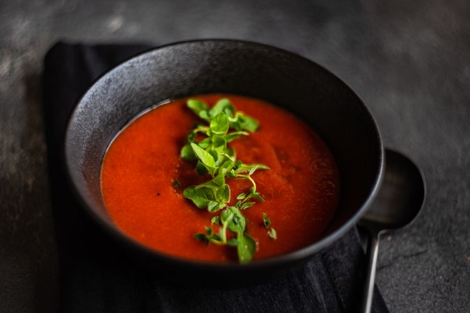 Gazpacho soup served in dark bowl on counter