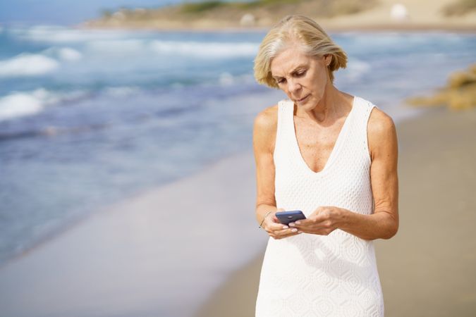 Mature female using her phone on a rocky beach