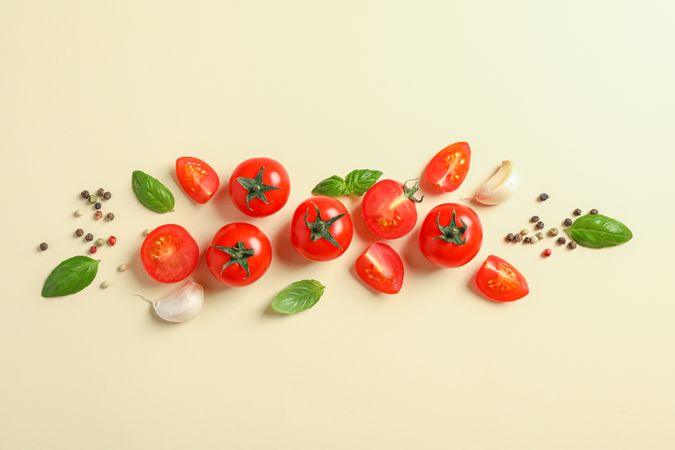 Flat lay composition with fresh cherry tomatoes, pepper, garlic and basil on color background, space for text. Ripe vegetables