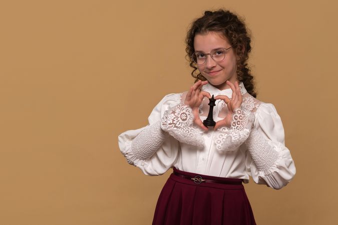 Young girl with glasses holding black chess piece