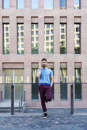 Young bearded man leaning outside talking on mobile phone