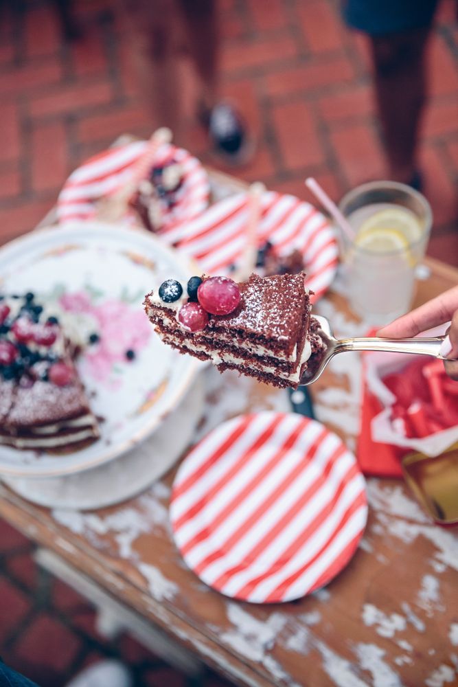 Hand with piece of cake in a summer party