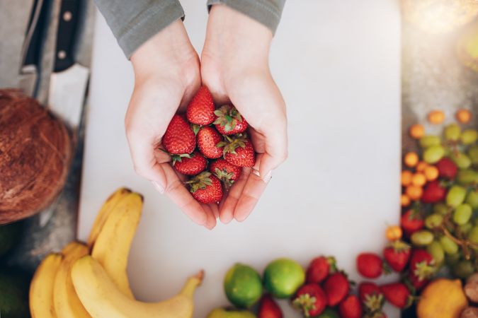 Female holding a handful of fresh strawberries