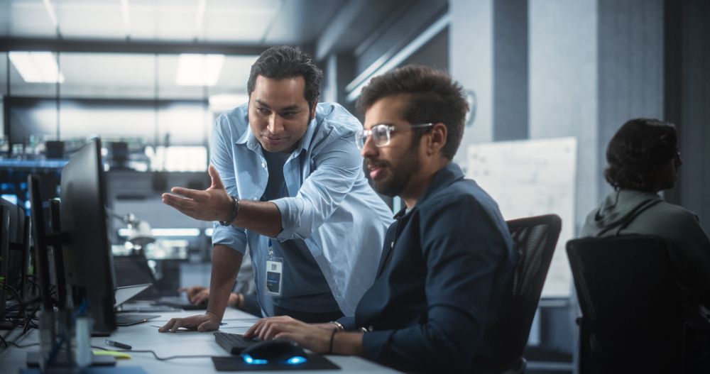 Creative Team of Indian Specialists Having a Conversation at a Workplace Next to Computer.