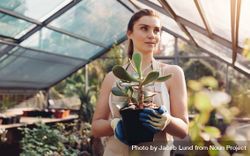 Beautiful young woman with a cactus plant in greenhouse 5XPWK5