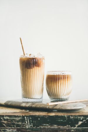 Two cups of iced coffee in clear classes with eco friendly straight on light background