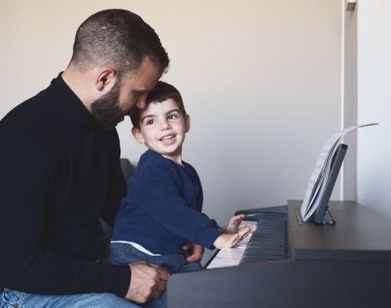 Father teaching son to play piano