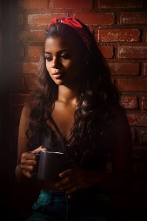 Woman in a dark top holding a mug standing indoor