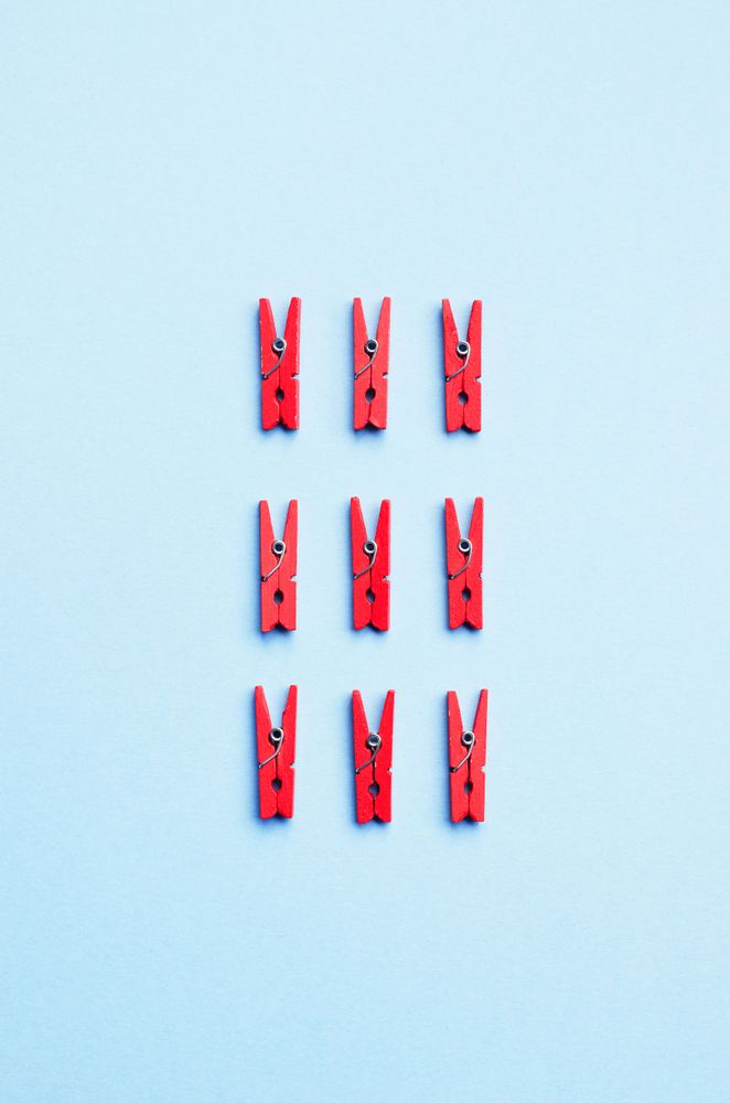Red clothes pins on light blue background