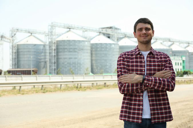 Young man against grain silos. Agriculture business