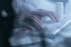 Doctor working at computer keyboard through X-ray film