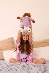 Girl holding teddy bear above head in bedroom.