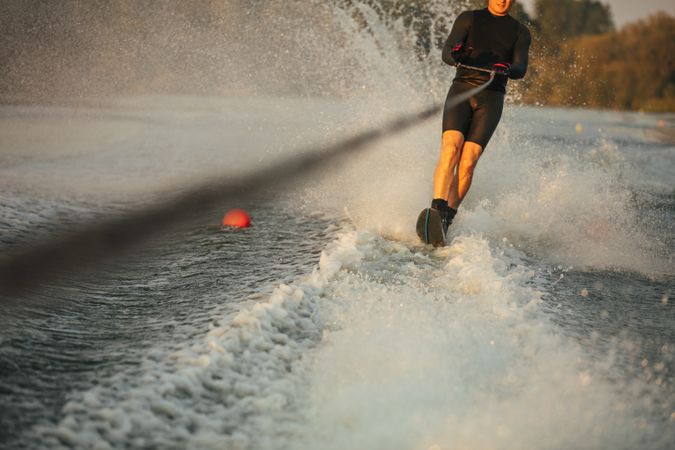 Man riding wakeboard on wave of motorboat in a lake
