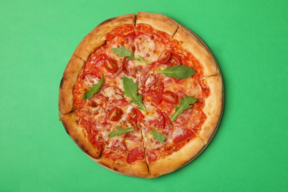 Tasty pizza with tomato on green background