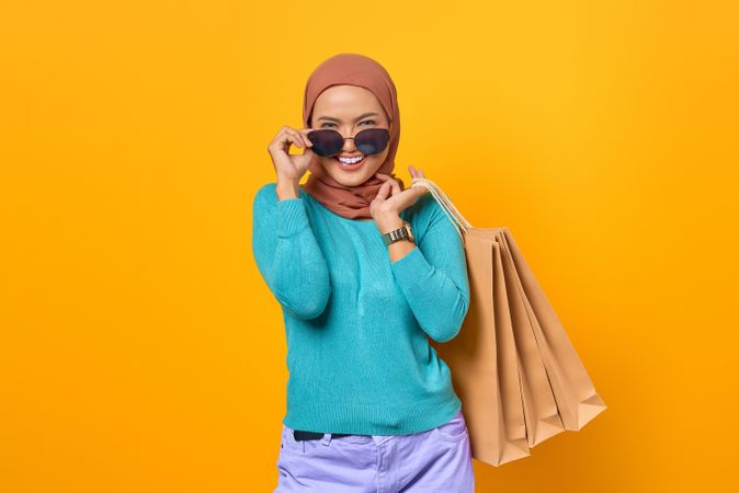 Muslim woman adjusting her sunglasses with shopping bags on her back