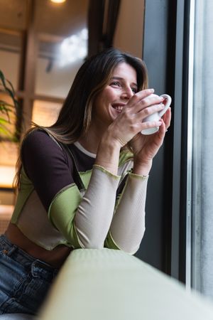 Cheerful woman with cup of coffee in cafe