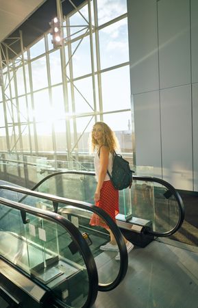 Active woman standing at escalator and about to go down