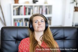 Blonde young woman listening to music on headphones while relaxing on sofa 41laKN