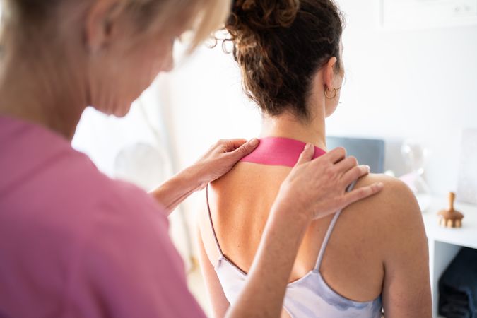 Physical therapist placing kinesiology tape on client