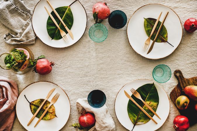 Fresh table setting on brown table cloth, leaves on bright plates, fruit, with copy space