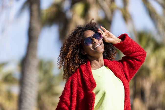 Smiling female in red jacket smiling in the sun on street with palm trees