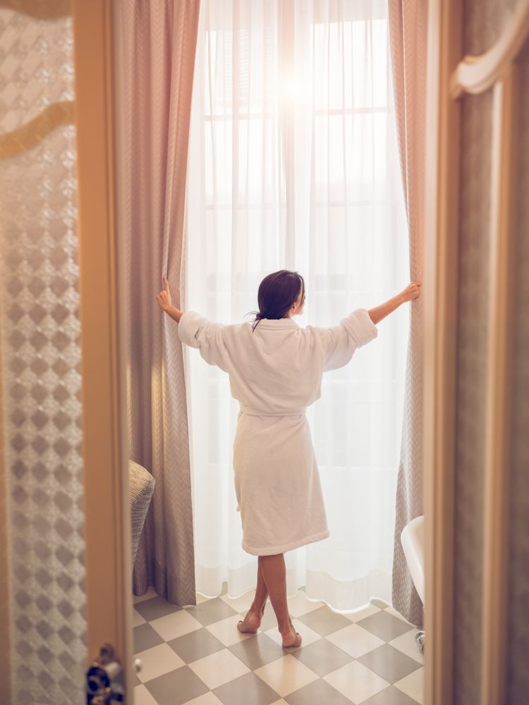 Unrecognizable female near window in hotel bathroom