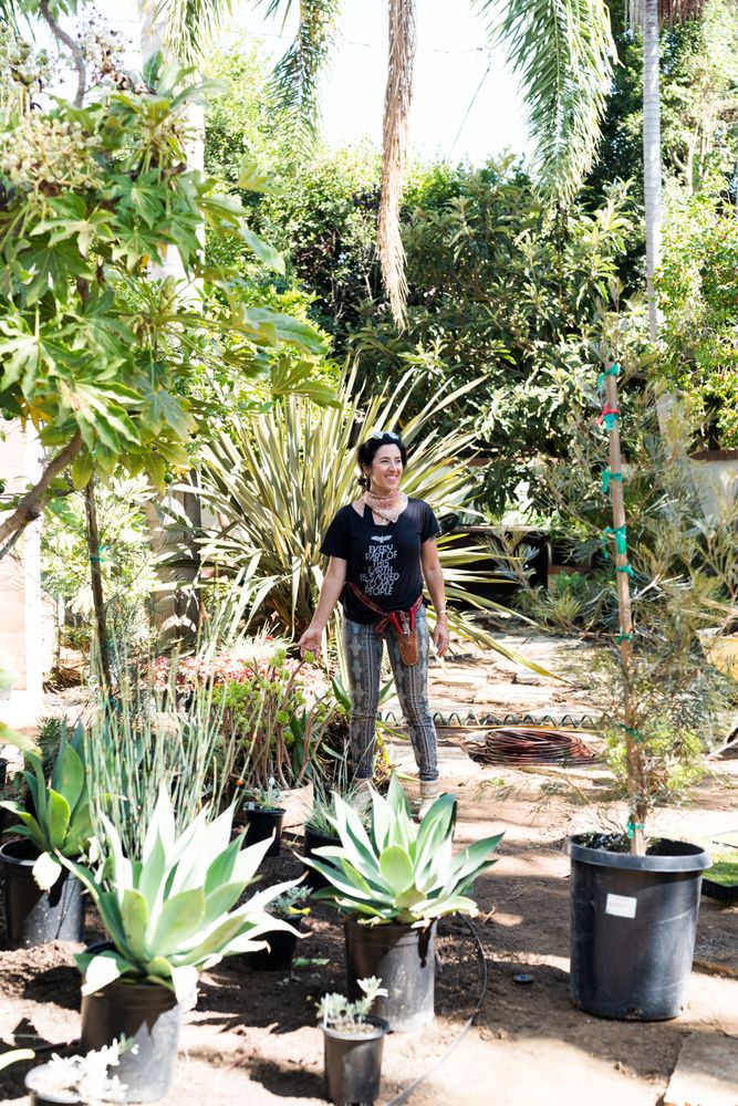 Female contractor working outside surrounded by potted plants and trees