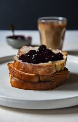 Toasted brioche butter and jam coffee in background