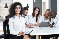 Curly haired business leader smiling in office looking at camera