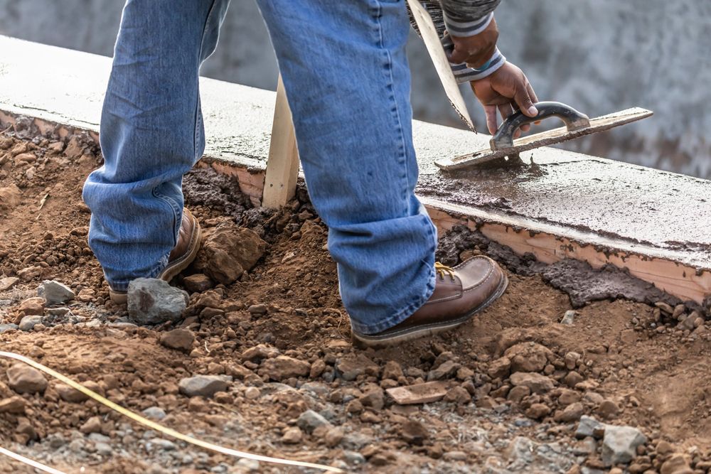 Construction Worker Using Wood Trowel On Wet Cement Forming Coping Around New Pool