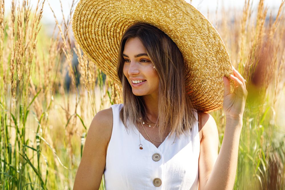 Portrait of happy female in a field outside in sundress and sunhat