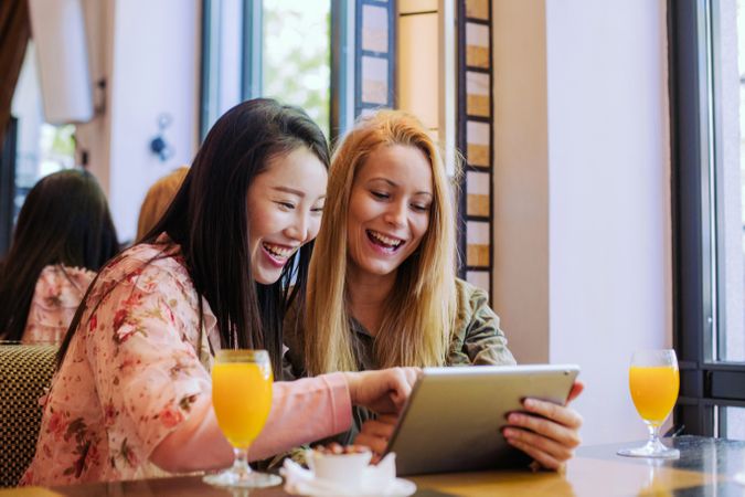 Female friends using tablet in cafe