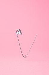 Close up of one opened safety pin on pink background