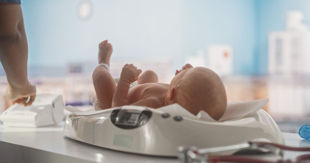 Newborn Infant Lying on Modern Digital Baby Scales in a Maternity Hospital Ward.