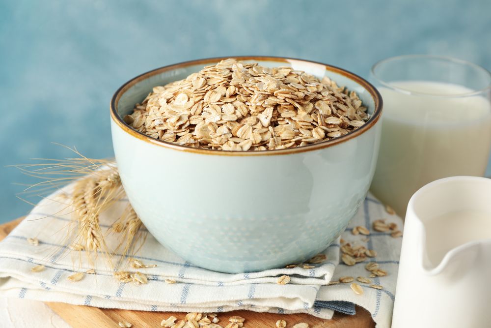 Composition with oatmeal flakes and milk on table. Cooking breakfast