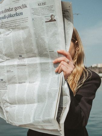 Blonde woman reading a newspaper outdoor