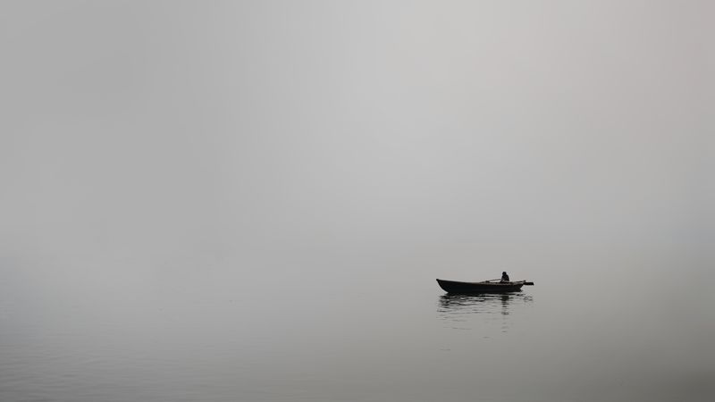 Grayscale photo of person riding on boat on body of water