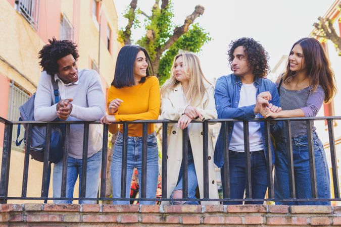 Portrait of happy male and female friends chatting in street outside