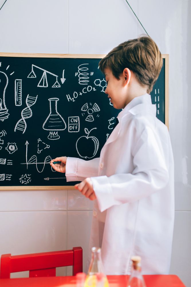 Boy showing drawings on chalkboard with marker