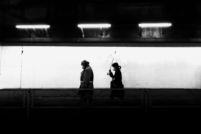 Grayscale photo of two people walking on sidewalk