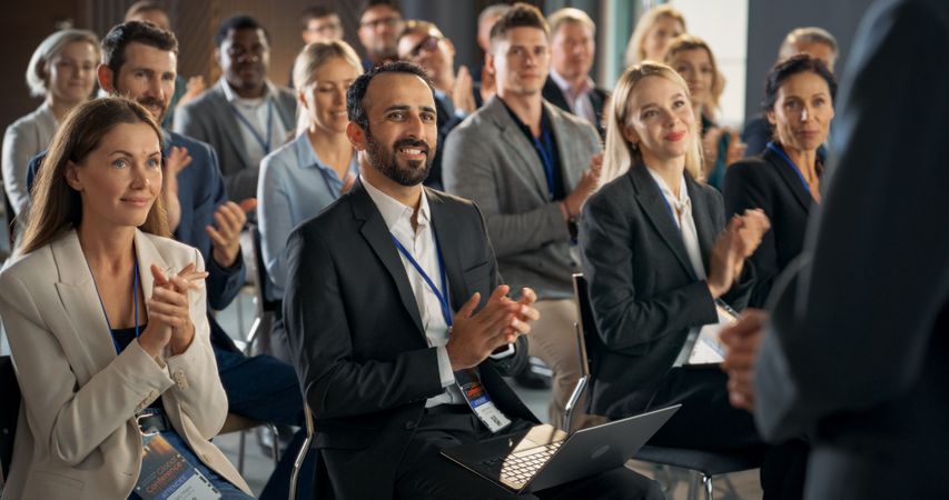 Back View Of Startup CEO Gesturing And Pitching Innovative Product Or Service to Room Full of Diverse Investors.
