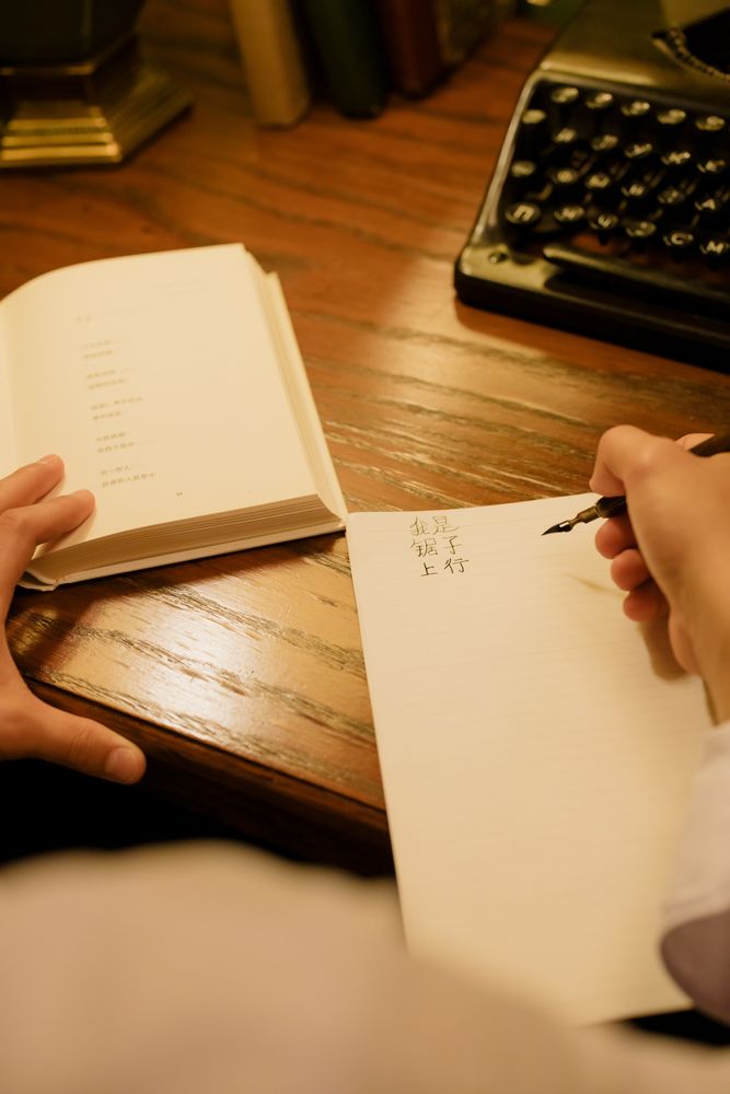 Person writing on a paper beside typewriter