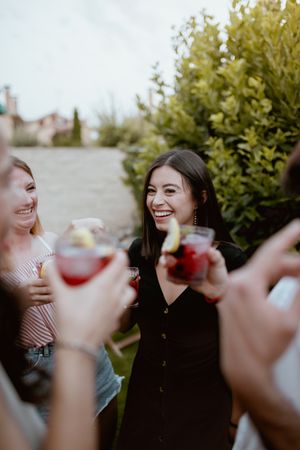 Group of cheerful friends clinking glasses at party