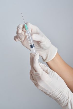 Unrecognizable doctor with vaccine in syringe