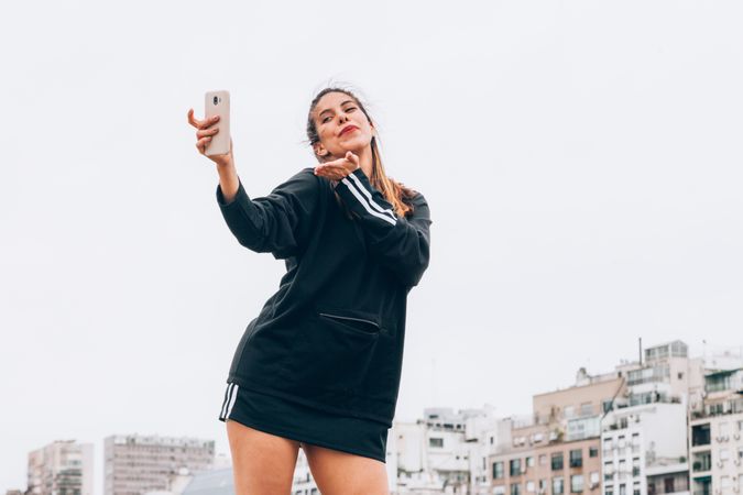 Content young woman in casual wear taking selfie at city street